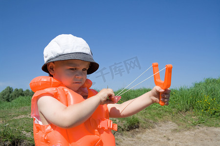 弹弓造型摄影照片_男孩拿着一把橙色弹弓