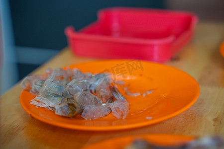 橙盘上一堆剥皮的虾壳