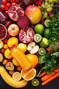 各种各样的彩虹色水果和蔬菜，在深色乡村表面的瓶子里放着冰沙。