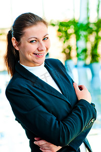 仅限内部摄影照片_在模糊的办公室内部背景中微笑的成功女商人的画像
