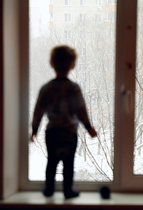 人的外轮廓摄影照片_男孩正透过窗户往外看。