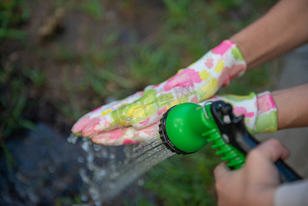 女人戴着花园手套的手是从软管里洗出来的