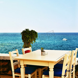 桌子有水摄影照片_希腊小酒馆和大海中的一张有盖桌子。