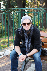 坐在长凳上的年轻时尚男士