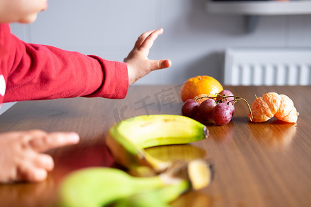 婴儿的手在木桌上操纵不同的水果