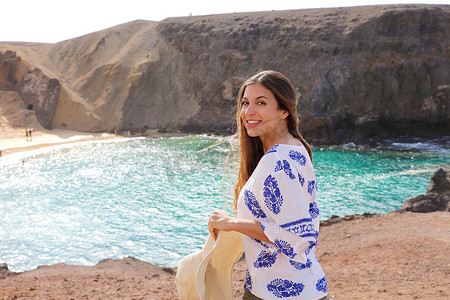 约为摄影照片_背景为 Playa Papagayo 景观的美丽旅游女性画像。