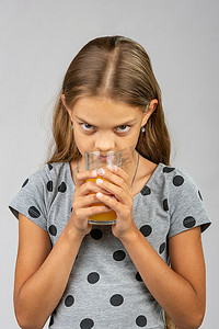 喝果汁的女孩摄影照片_一个十岁的女孩喝果汁并享受香味