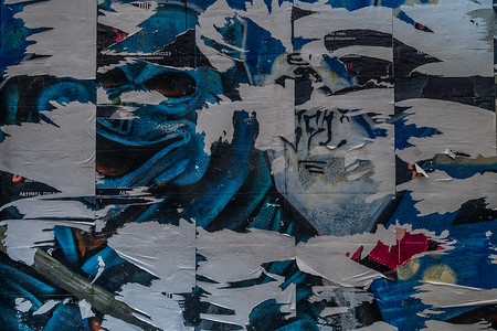 垃圾旧墙上的彩色撕破海报作为创意和抽象背景
