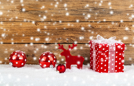 喜庆背景花纹摄影照片_圣诞节的红色礼物在有雪的木背景
