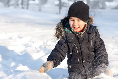雪地里玩耍摄影照片_快乐的男孩在雪地里玩耍
