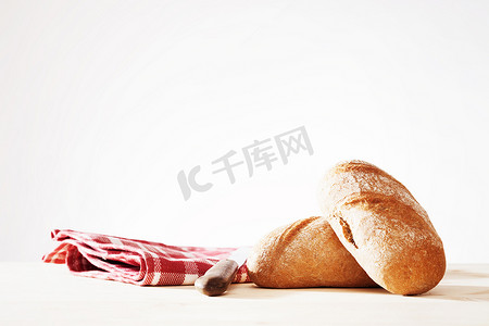 两个全麦面包，一条毛巾和一把旧面包刀