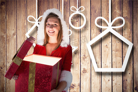 穿着圣诞老人服装的微笑女人在木质背景下打开礼盒