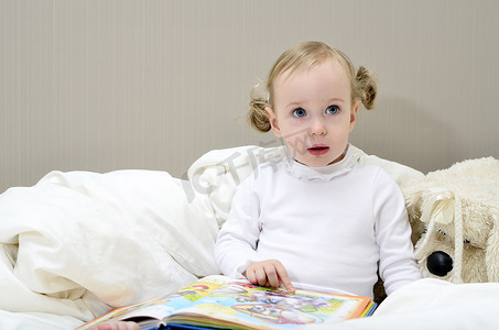 坐在床上看书的小女孩