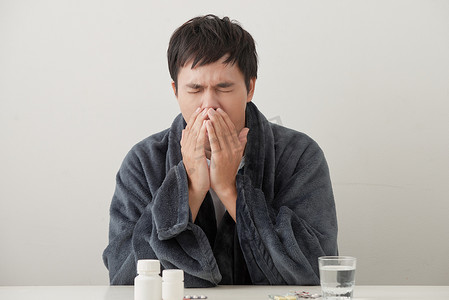 在沙发上拿着纸巾清洁流鼻涕的年轻病人和生病的人，在流感和流感保健概念中被冬季流感病毒感染，感觉温度不好。