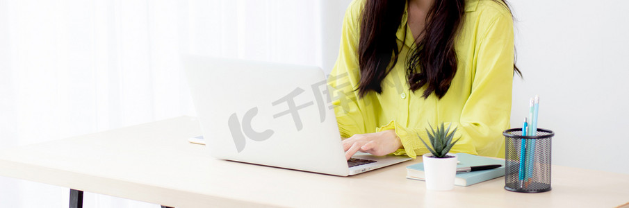 年轻的亚洲女商人在家庭办公室的办公桌上使用笔记本电脑工作，自由职业者在桌上的笔记本上看和打字，女性在线学习的生活方式，商业和教育理念。