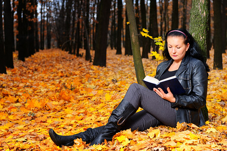 有魅力的女人在秋天的森林里读书