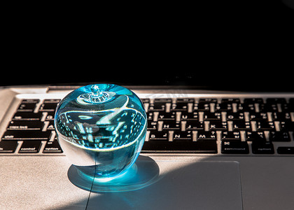 玻璃水晶蓝色苹果特写镜头在膝上型计算机键盘的。