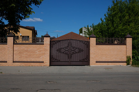 木蓝天背景下，街道上有铁艺门的轻砖栅栏