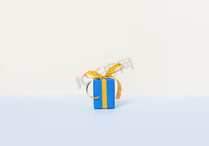 在柔和的背景上有黄色丝带的蓝色礼品盒。