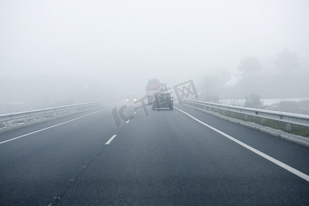 大雾预警摄影照片_“雾蒙蒙的灰色道路，汽车驶入雾中”