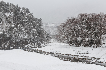 下雪乡村摄影照片_冬季降雪的白川乡村和索桥。