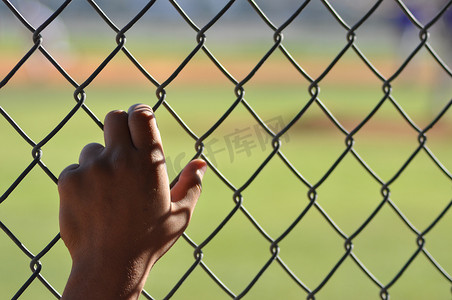 孤独的手在棒球场的链环围栏上