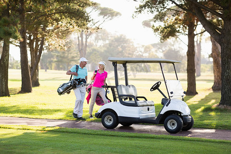 微笑的成熟高尔夫球手夫妇乘高尔夫球车