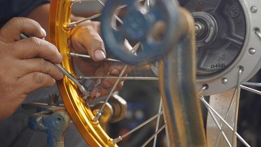 技术员工作的摩托车车轮在机械工具新钢轮上有辐条编织