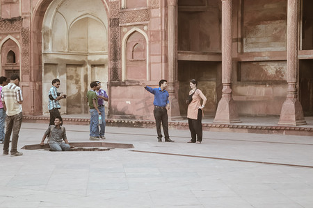 参观引导摄影照片_红堡，印度德里，2018 年 5 月 - 一位专家导游（导游）通过提供有关建筑的文化、历史和遗产重要性的信息来协助外国游客度假。