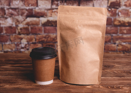木制背景上的咖啡和牛皮纸袋袋靠在砖墙上