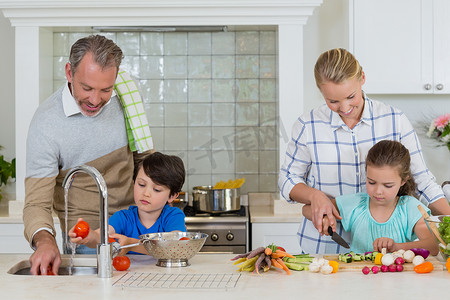 父母协助孩子在厨房切菜和清洗蔬菜
