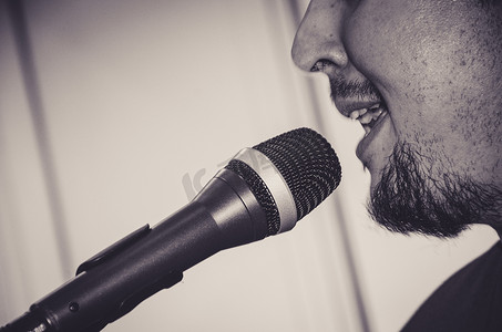 歌手唱歌摄影照片_歌手的特写脸，带麦克风，在黑白背景下唱歌