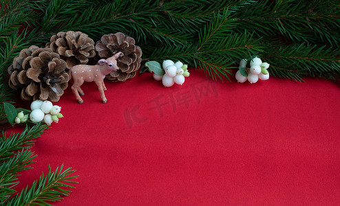 新年贺卡创意摄影照片_“三个松果、一只鹿和带有白色浆果的云杉枝。新年和圣诞节的概念。您的文字空间”