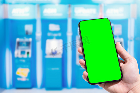 在百货商店的 ATM 机蓝色模糊中，女性使用手持智能手机模糊图像触摸抽象模糊。