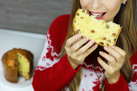 年轻女子在圣诞假期吃一片 Panettone 传统意大利蛋糕的裁剪照片