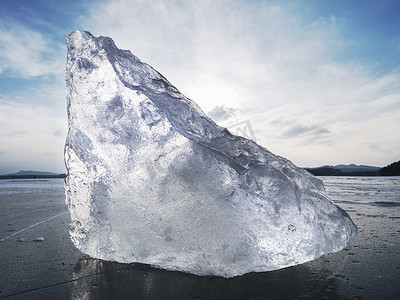 发光的太阳摄影照片_冻湖上的抽象浮冰、风化冰的质地和闪闪发光的太阳