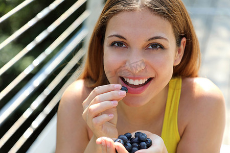 相当开朗的女孩在城市公园吃蓝莓。