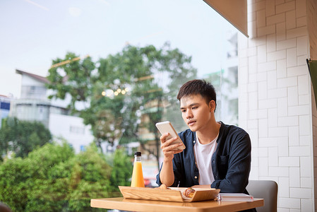 男人在下午茶时间使用手机，使用移动智能手机，使用无线通信的物联网生活方式和使用智能手机的互联网。