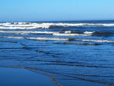 大海浪拍岸摄影照片_“晴朗的日子里，海浪拍岸”