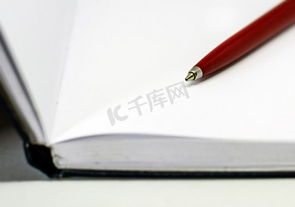 日记页摄影照片_打开笔记本空白页上的红色圆珠笔