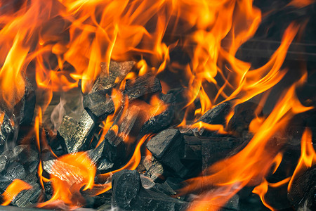 带有红色火焰、热木炭煤球和余烬的炽热明火的烧烤坑