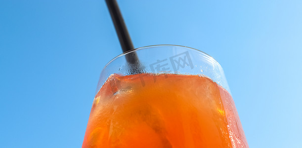 在蓝天背景下加冰的清爽橙色夏季鸡尾酒。