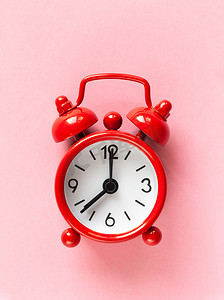 浅粉色背景上的红色小闹钟，平躺，宏观。