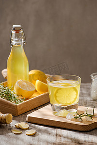 质朴的木桌上放着柠檬、生姜、迷迭香和冰的清爽夏日饮品，复制空间