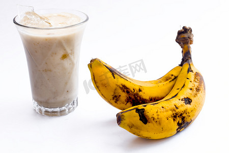 香蕉牛奶摄影照片_生有机新鲜香蕉及其冰沙或奶昔或香蕉牛奶，放在玻璃杯中，用白色隔开。