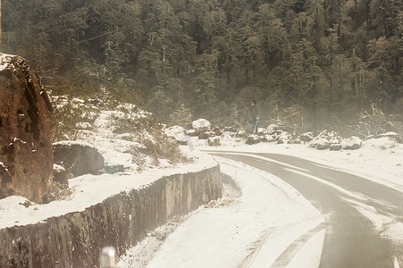 风雪同行摄影照片_冬天多风雪雾湿滑泥泞平坦的喜马拉雅山路。 