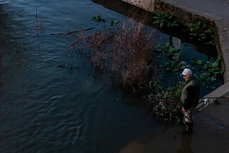 日落时分，叔叔在泰晤士河畔钓鱼。