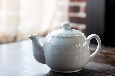 木桌上有茶的白色茶壶