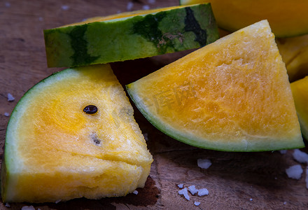 新鲜多汁的黄色西瓜在旧木背景上切成三角形。