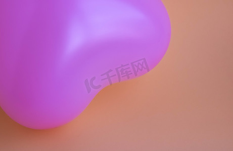 粉红色背景上心形的紫色气球。